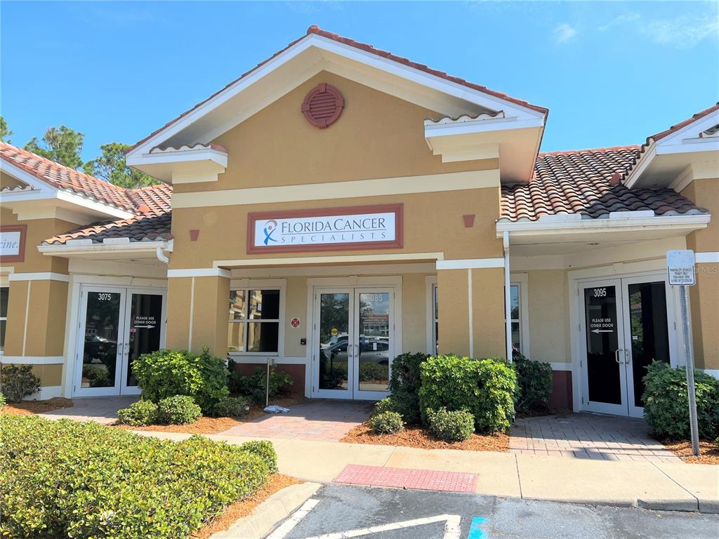 The exterior of a commercial building features a Florida Cancer Specialists sign above glass doors — 3075 BOBCAT VILLAGE CENTER ROAD, NORTH PORT, FL