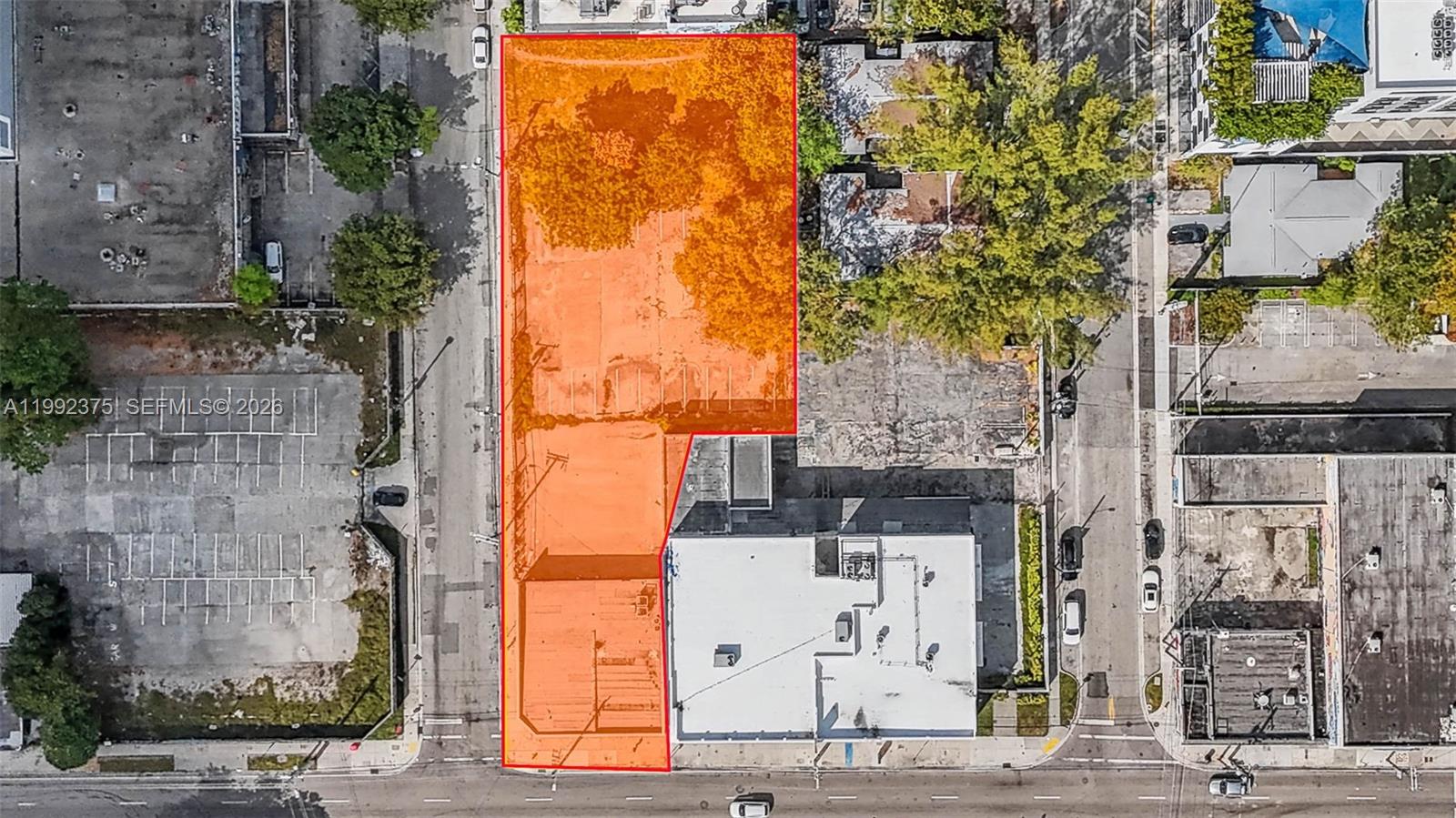 An aerial view shows an L-shaped vacant lot outlined in orange next to a building — 2500 N Miami Ave, Miami FL 33127, MIAMI, FL