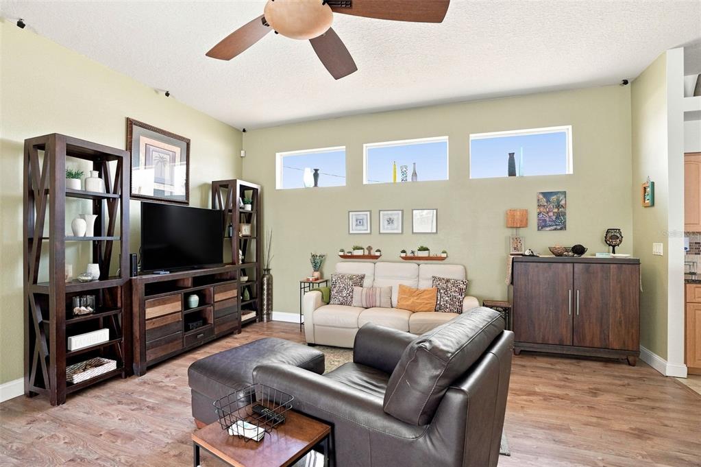 A living room features a dark wood entertainment center, a beige sofa, and a leather armchair — 11399 REDGATE STREET, SPRING HILL, FL