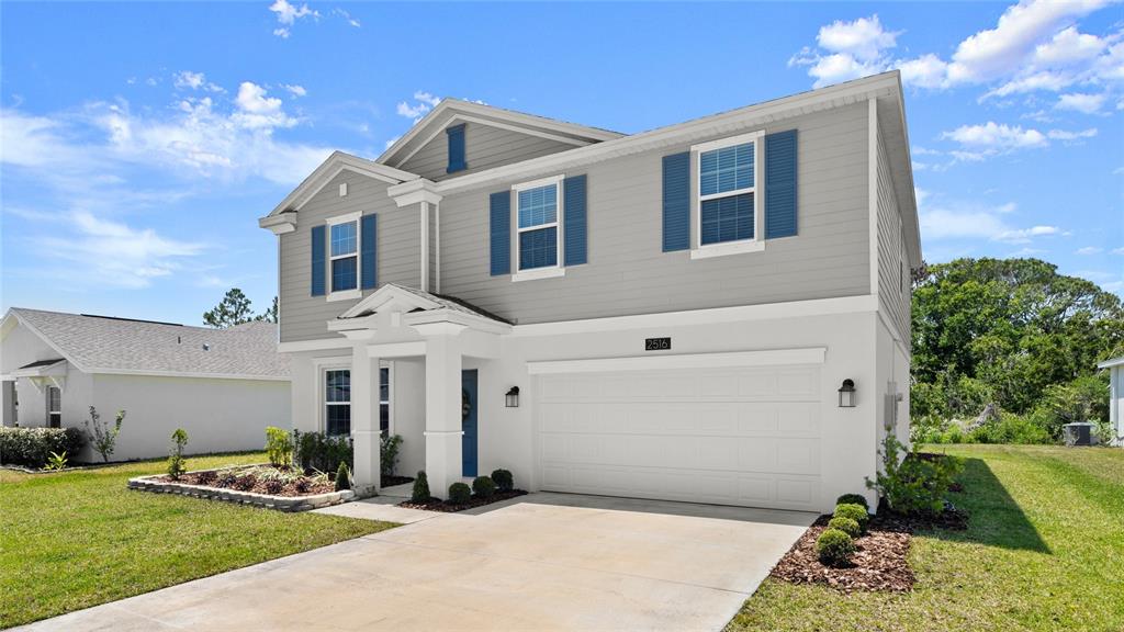 A two-story house with gray siding, white stucco, blue shutters, and a two-car garage — 2516 HOPTREE LANE, EDGEWATER, FL