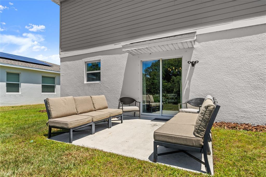 A concrete patio with outdoor furniture sits against the back wall of a two-story house — 2516 HOPTREE LANE, EDGEWATER, FL