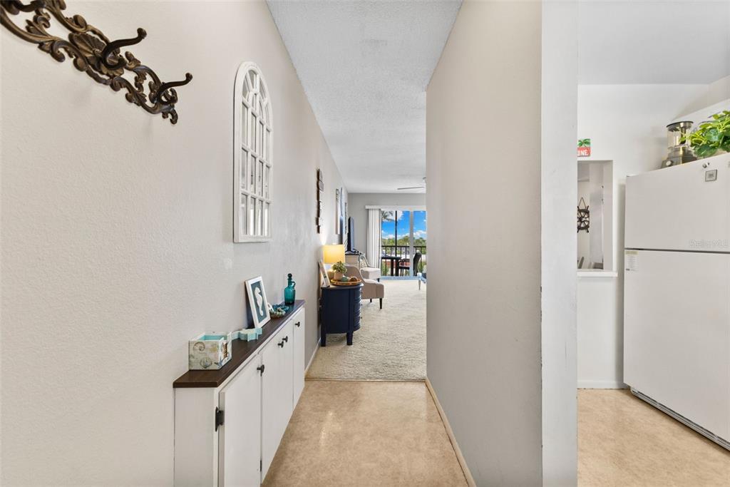 A hallway with a white cabinet and wall decor leads toward a living area — 915 BEACH ROAD UNIT 318, SARASOTA, FL
