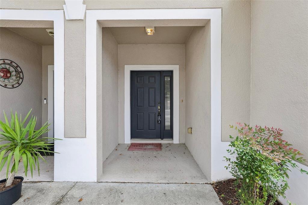 A dark gray front door with a side light sits within a recessed entryway — 14261 TURNING LEAF DRIVE, ORLANDO, FL