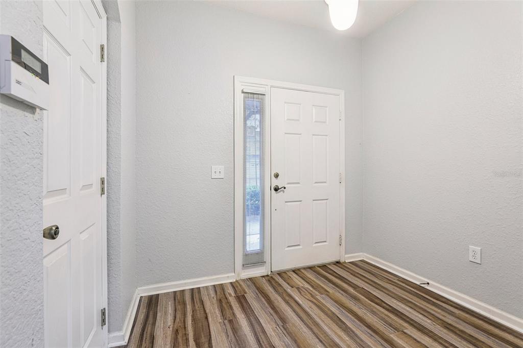 An entryway features light gray walls, wood-look flooring, a white front door, and a closet — 14261 TURNING LEAF DRIVE, ORLANDO, FL