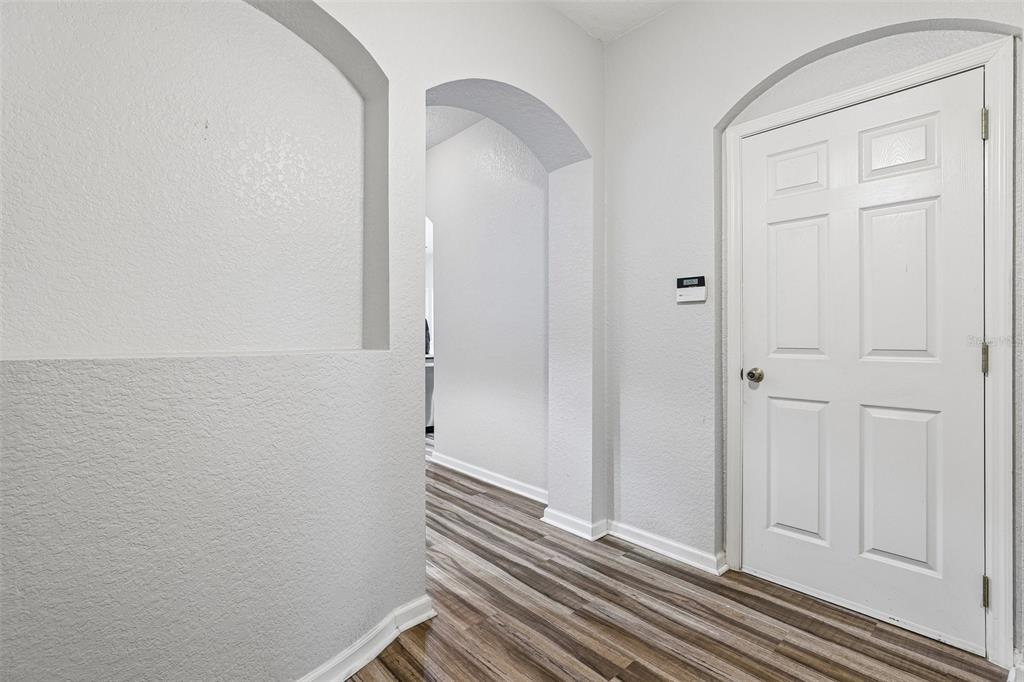 A hallway features wood-look flooring, an arched entryway, a recessed wall niche, and a white door — 14261 TURNING LEAF DRIVE, ORLANDO, FL