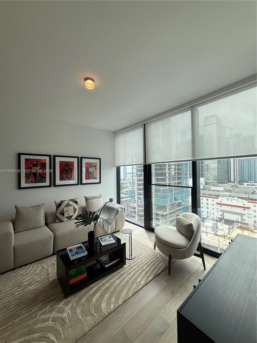 A modern living room features a beige sofa, a black coffee table, and floor-to-ceiling windows — 20 NE 11th St # 2909, Miami FL 33132, MIAMI, FL