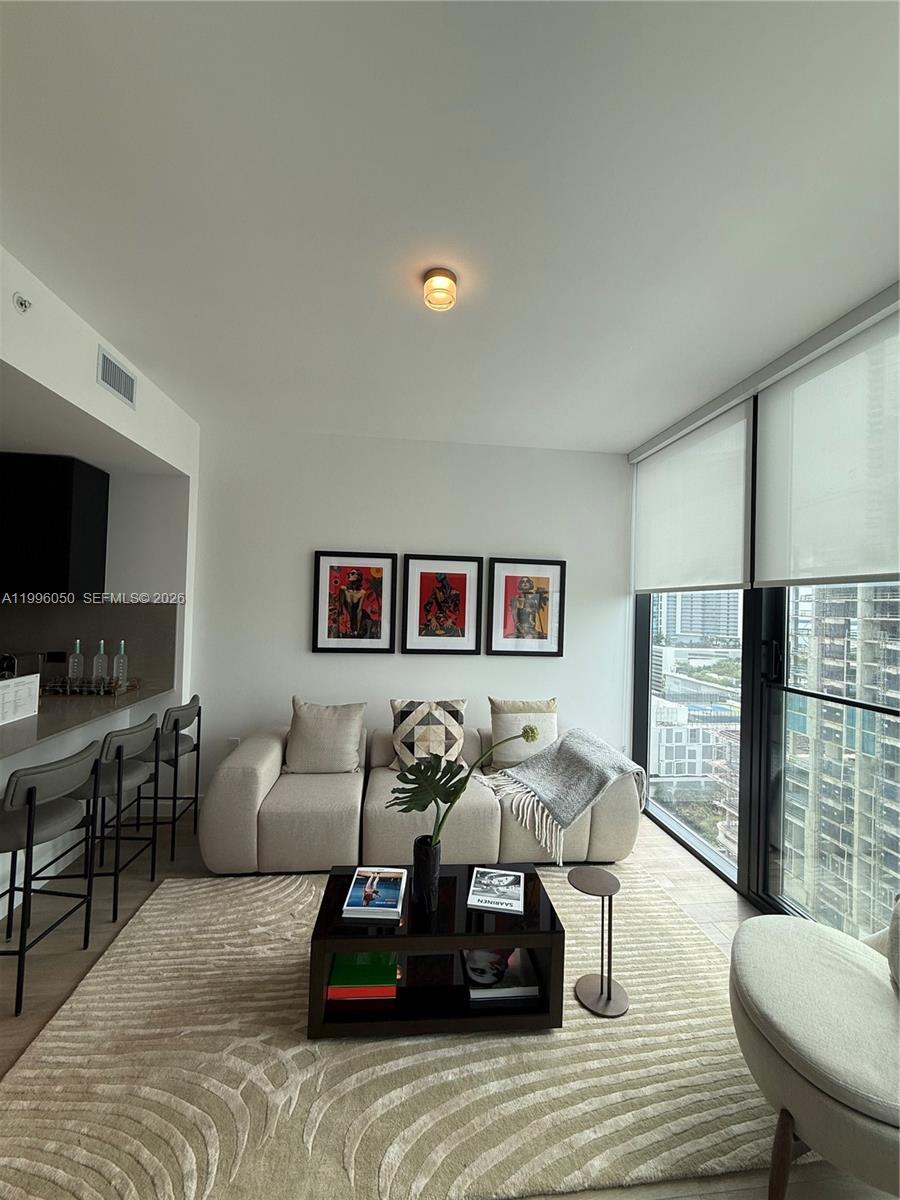A modern living room features a beige sofa, a coffee table, and floor-to-ceiling windows — 20 NE 11th St # 2909, Miami FL 33132, MIAMI, FL