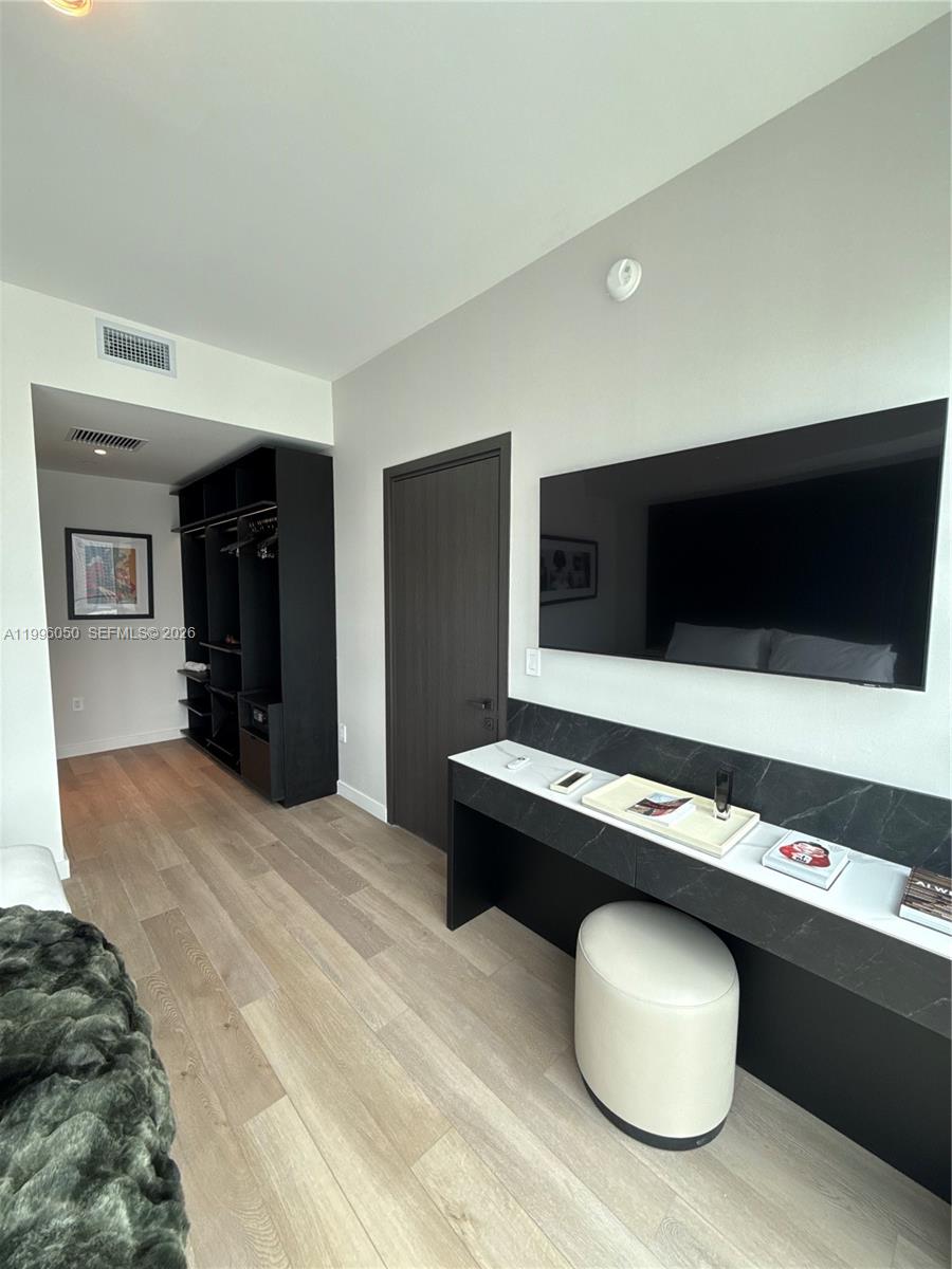A bedroom features a wall-mounted television, a black desk, a white ottoman, and an open closet — 20 NE 11th St # 2909, Miami FL 33132, MIAMI, FL