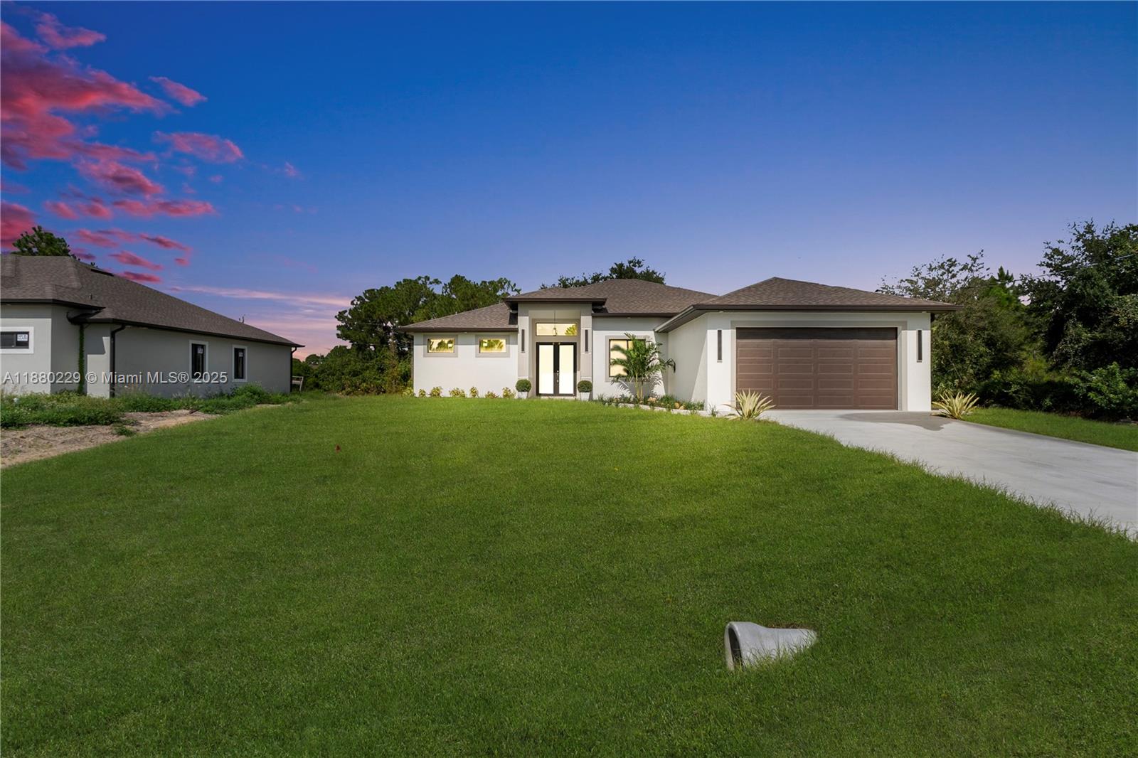 A modern single-story house with a brown garage door and a large front lawn — 1913 IRVING AVE, Lehigh Acres FL 33972, LEHIGH ACRES, FL
