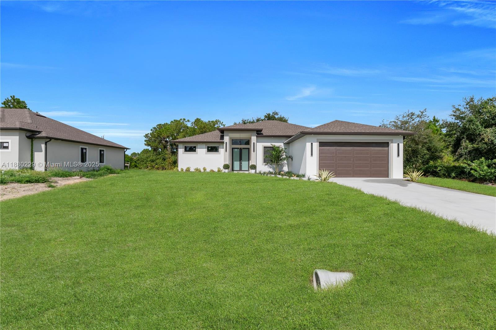 A modern single-story house with a brown roof and garage sits on a grassy lot — 1913 IRVING AVE, Lehigh Acres FL 33972, LEHIGH ACRES, FL