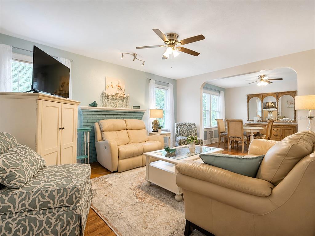 A living room with a brick fireplace, beige leather furniture, and an adjacent dining area — 112 S DIXIE AVENUE UNIT 2, FRUITLAND PARK, FL