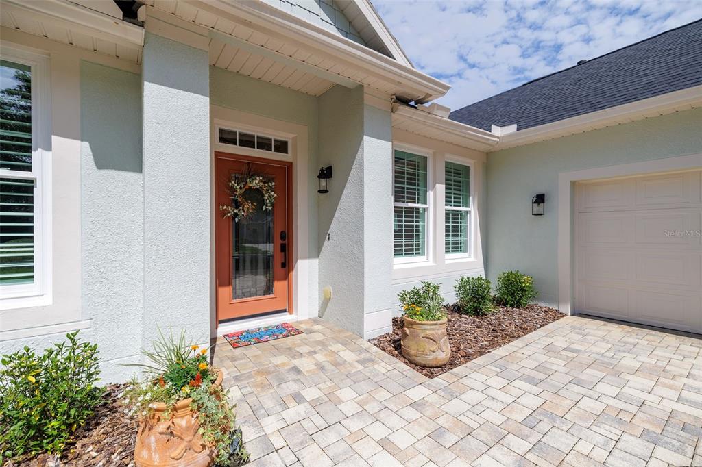 The exterior of a house features a paved walkway, a terracotta door, and landscaping — 309 BELLINGRATH TERRACE, DELAND, FL