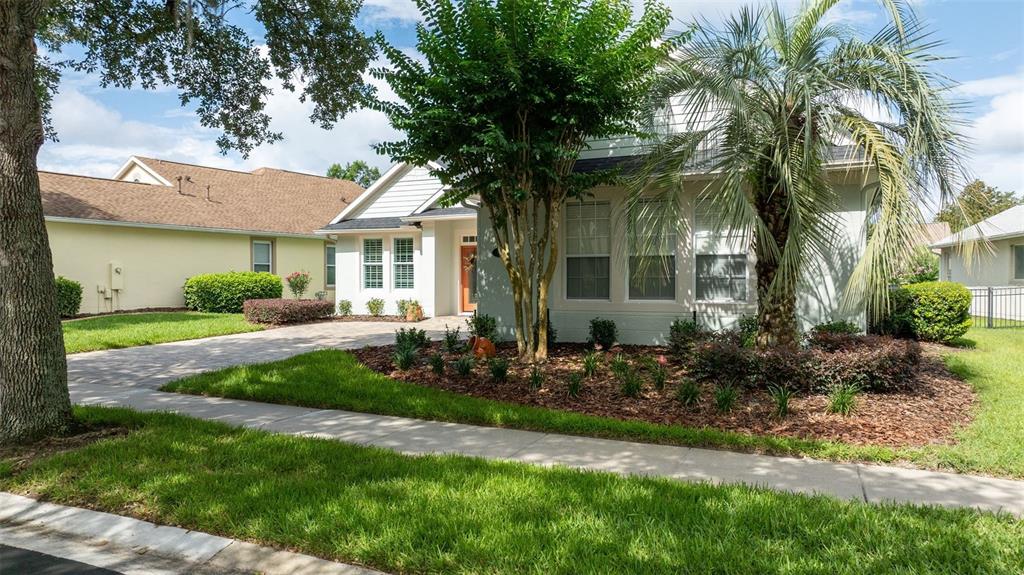 A light-colored house with a palm tree and a paved driveway in the front yard — 309 BELLINGRATH TERRACE, DELAND, FL