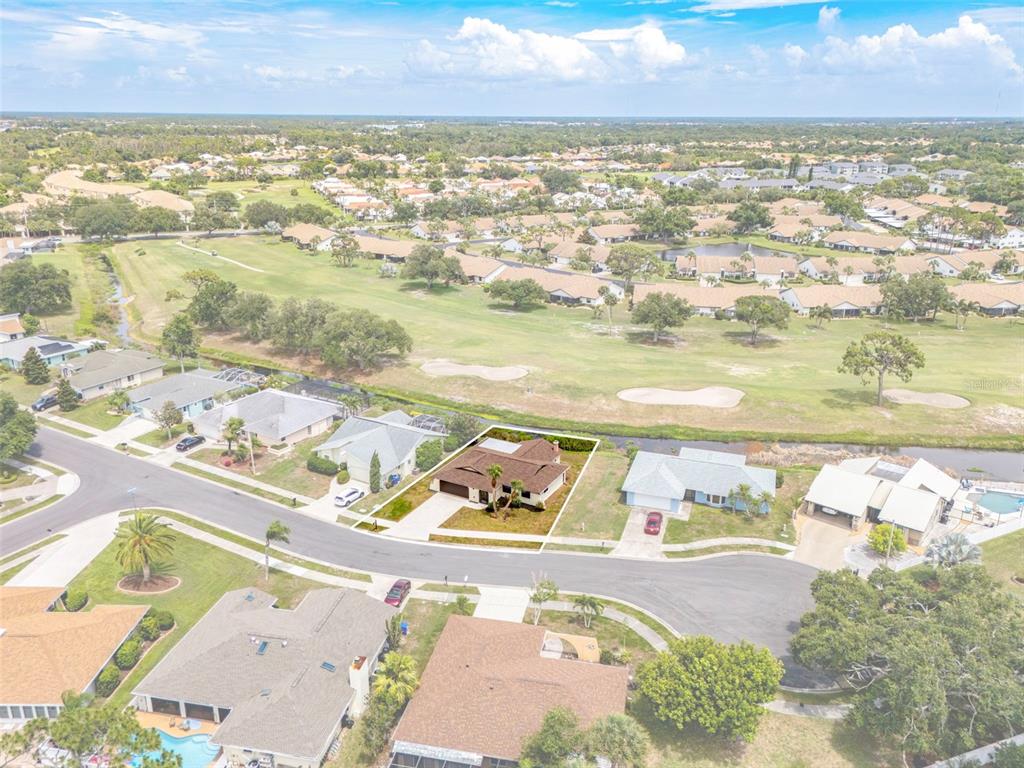 An aerial view shows a single-story house with a brown roof and a golf course — 1411 STRADA D ARGENTO, VENICE, FL