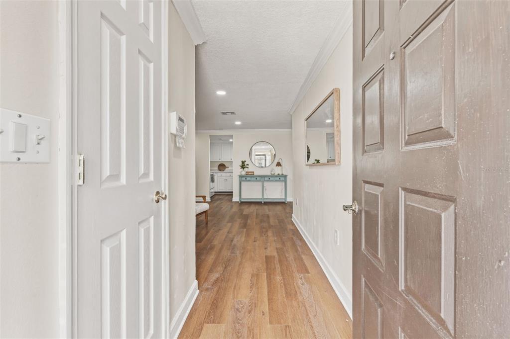 An entryway leads into a hallway with wood-look flooring, a console table, and a mirror — 1411 STRADA D ARGENTO, VENICE, FL