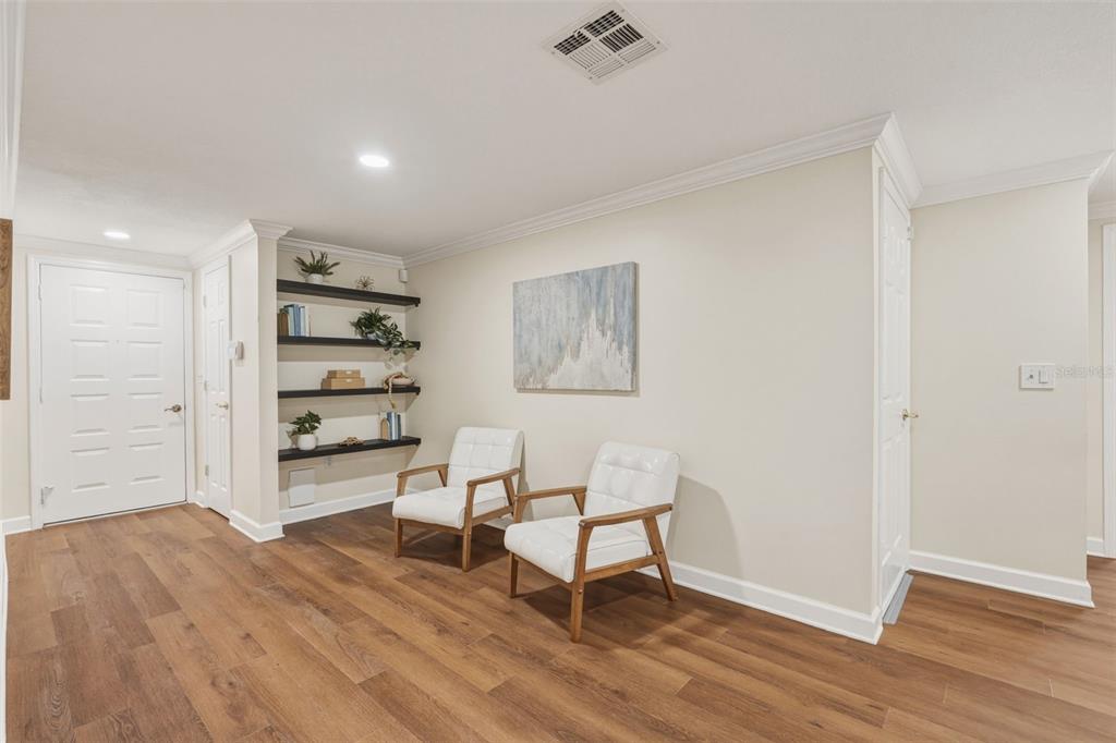 A room with wood-look flooring, two white chairs, wall-mounted shelves, and a piece of art — 1411 STRADA D ARGENTO, VENICE, FL