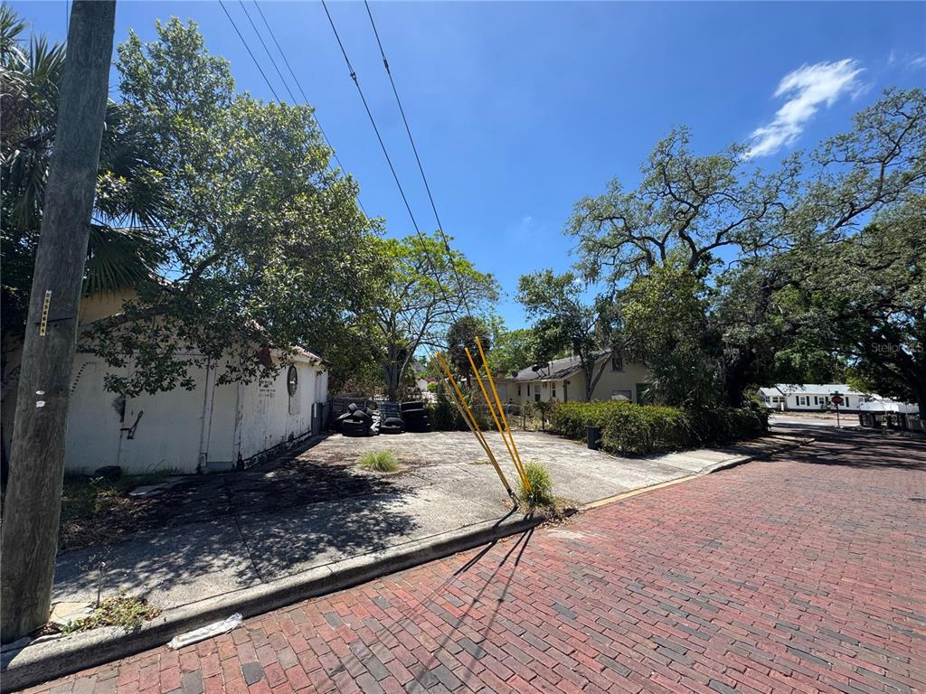 A paved lot with a small building and stacked tires sits beside a brick street — 72 ADA STREET, TARPON SPRINGS, FL