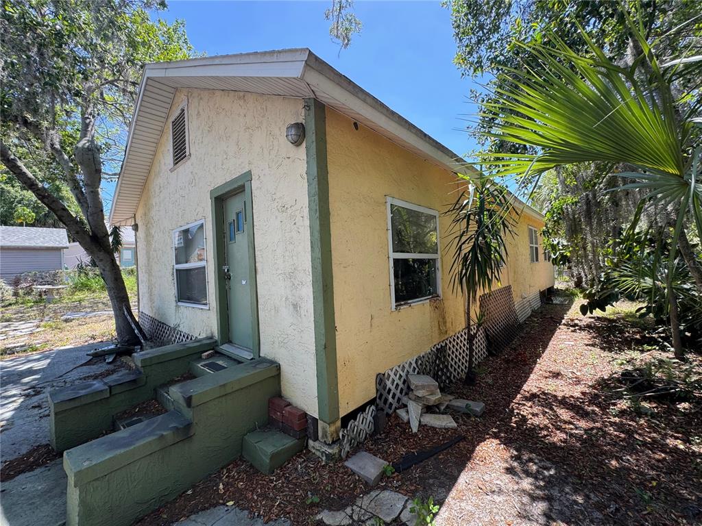 A yellow, single-story house with a green door and concrete steps sits on a lot — 72 ADA STREET, TARPON SPRINGS, FL