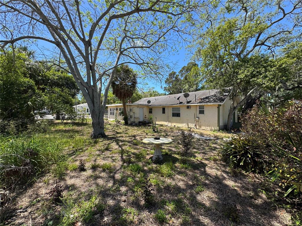 A single-story house with a light-colored exterior sits in a yard with large trees — 72 ADA STREET, TARPON SPRINGS, FL