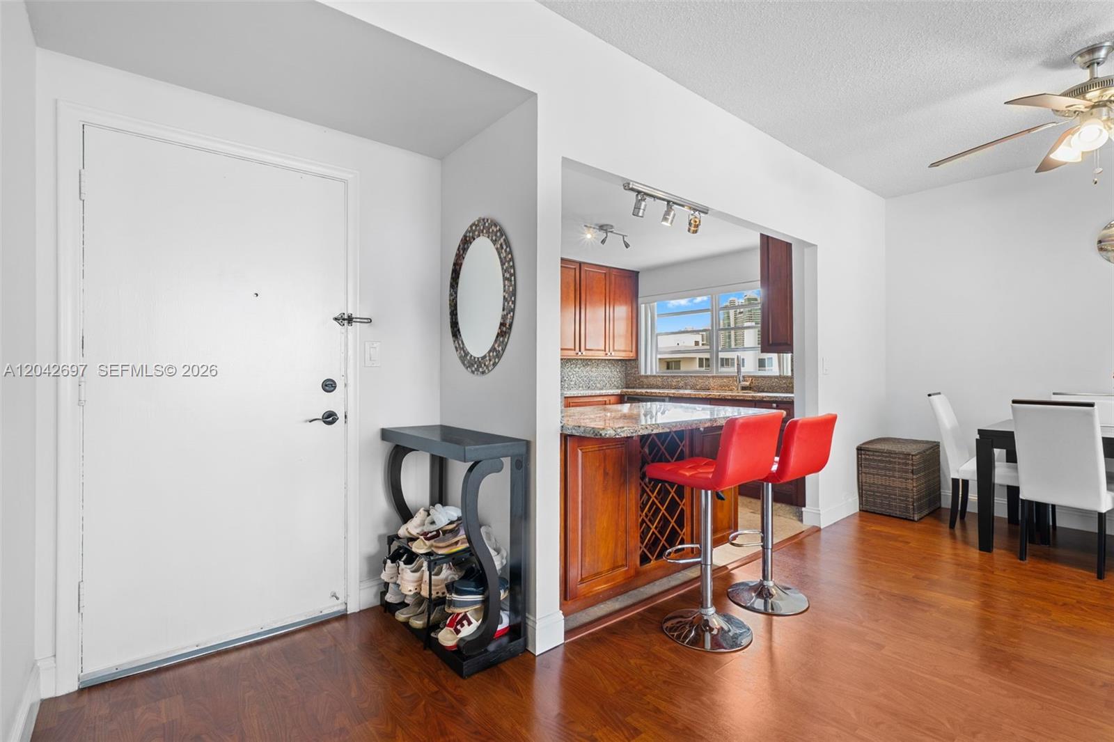 A kitchen with wood cabinets and a breakfast bar sits adjacent to a dining area — 1817 S Ocean Dr, Hallandale Beach FL 33009, HALLANDALE BEACH, FL