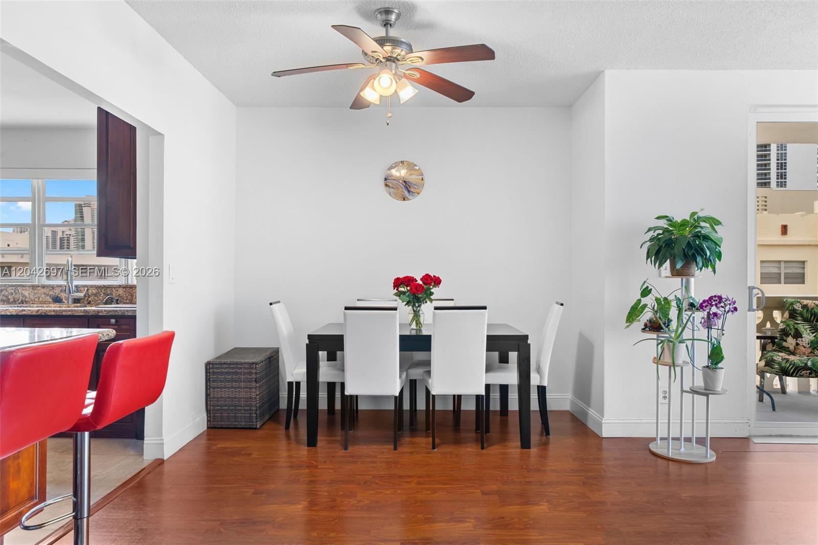 A dining area features a dark table with white chairs, wood flooring, and a ceiling fan — 1817 S Ocean Dr, Hallandale Beach FL 33009, HALLANDALE BEACH, FL