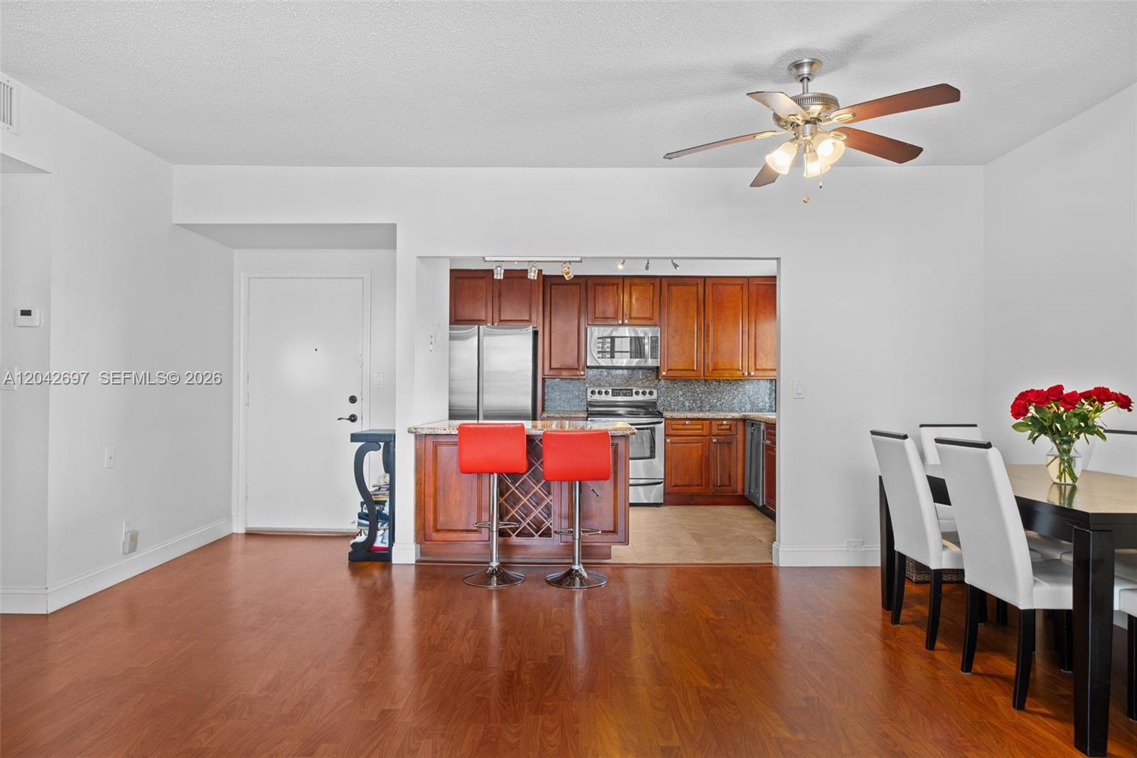 A kitchen with wood cabinets and a breakfast bar opens into a dining area — 1817 S Ocean Dr, Hallandale Beach FL 33009, HALLANDALE BEACH, FL