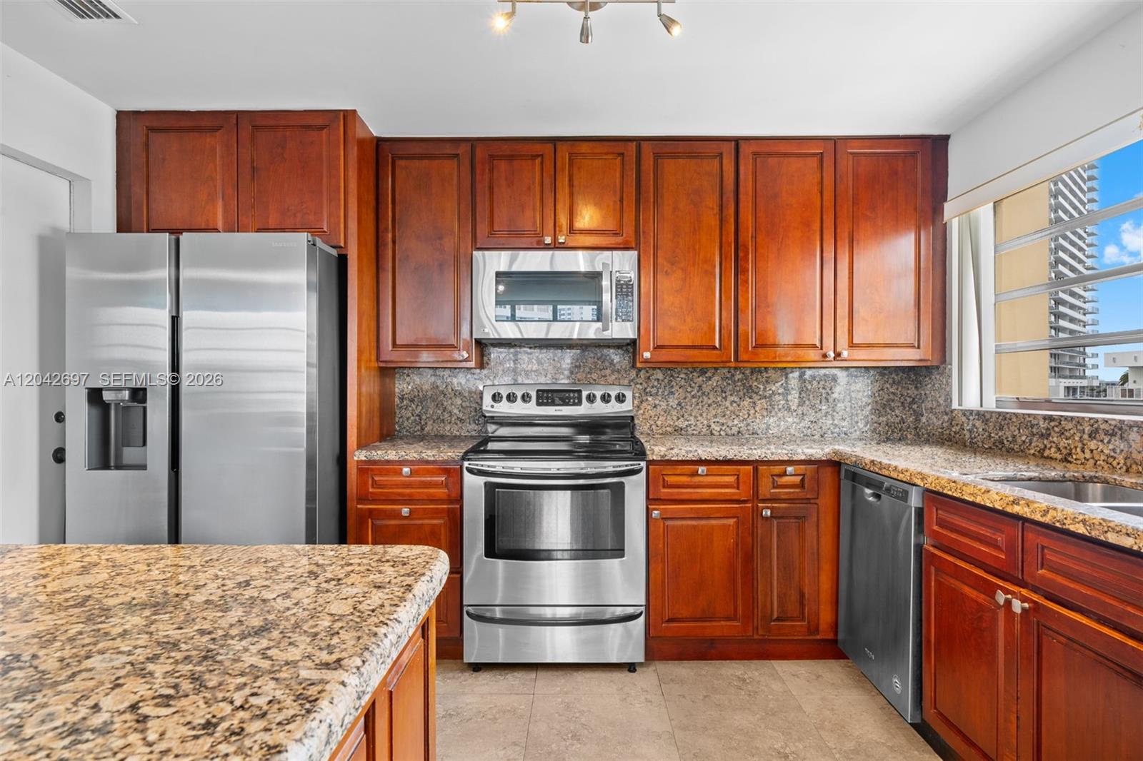A kitchen features cherry wood cabinets, granite countertops, and stainless steel appliances — 1817 S Ocean Dr, Hallandale Beach FL 33009, HALLANDALE BEACH, FL