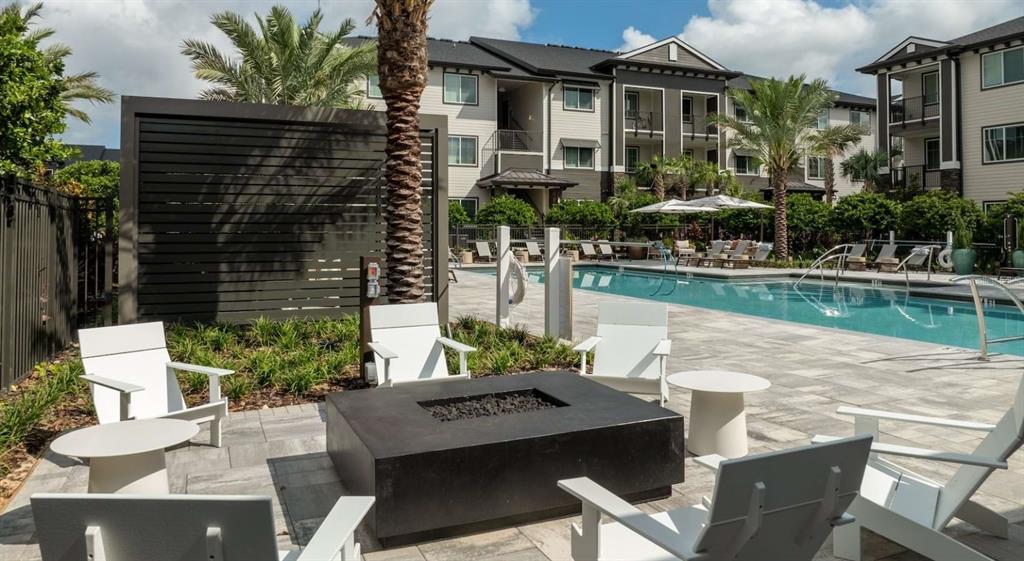 A square fire pit surrounded by white chairs on a patio next to a swimming pool — 5000 COLLINA TERRACE UNIT A2, CLERMONT, FL