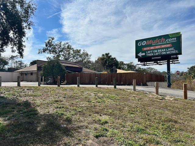 A large commercial billboard stands in front of a building enclosed by a wooden fence — 3468 E SEMORAN BOULEVARD, APOPKA, FL