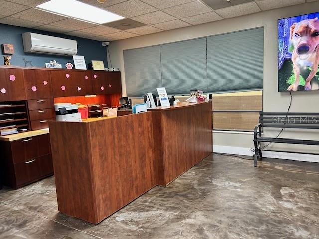 A reception area features a wooden desk, dark cabinetry, and a television displaying a dog — 3468 E SEMORAN BOULEVARD, APOPKA, FL
