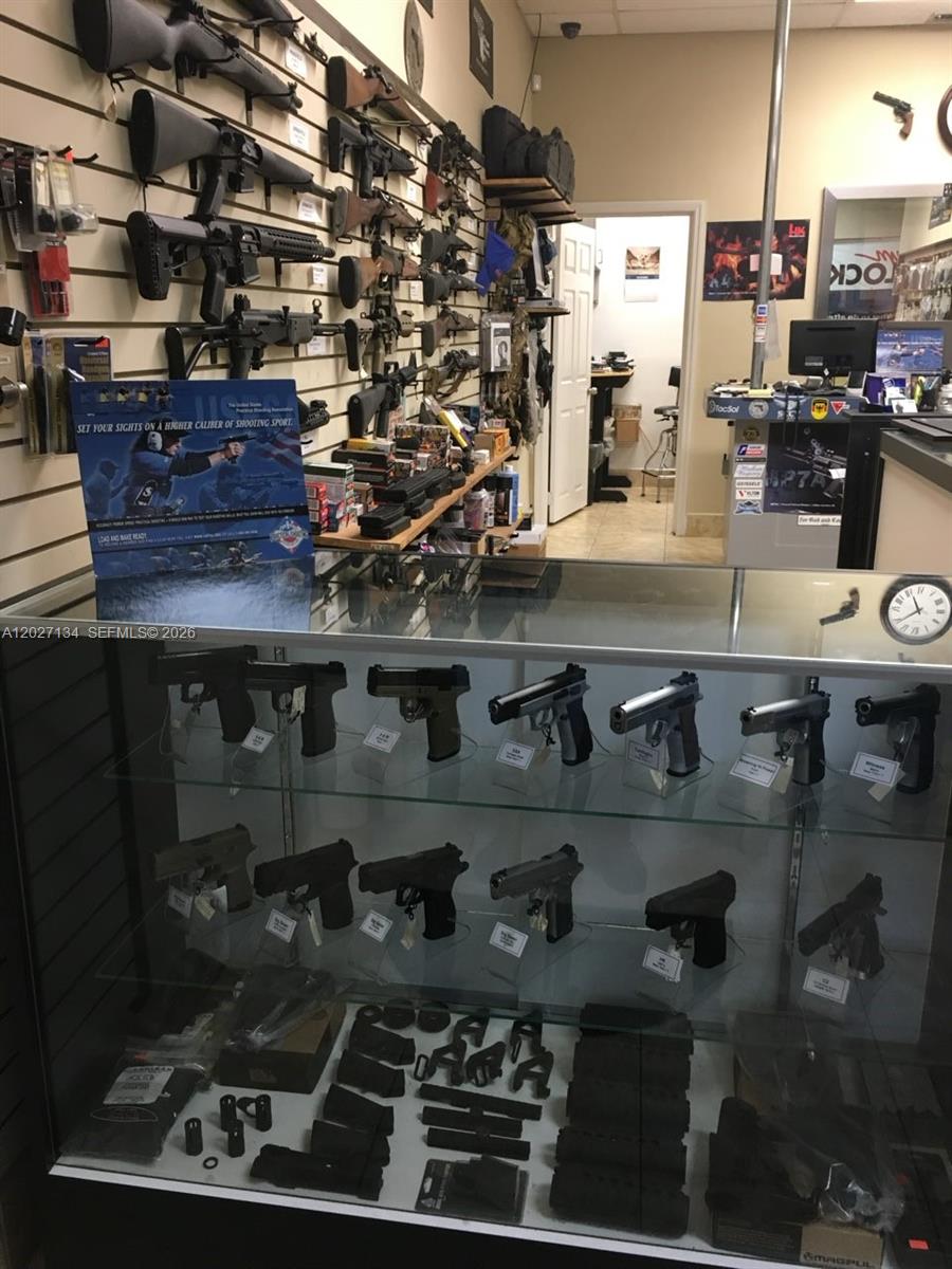 A retail store interior features a display case filled with handguns and wall-mounted rifles — 2005 W 62nd St, Hialeah FL 33016, HIALEAH, FL