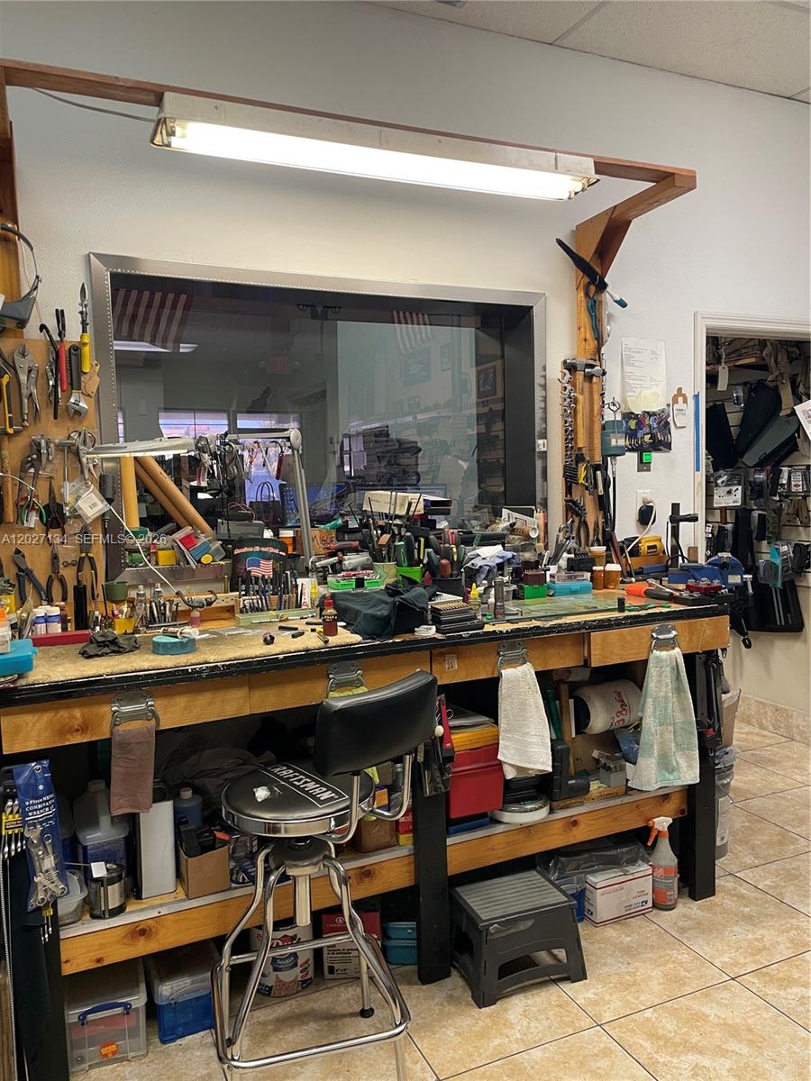 A cluttered workbench with tools and a stool sits in front of a large window — 2005 W 62nd St, Hialeah FL 33016, HIALEAH, FL
