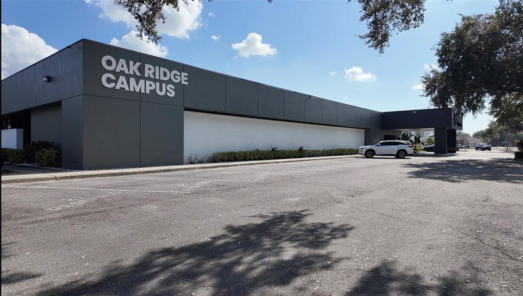 Exterior view of the Oak Ridge Campus building with a large parking lot in front — 6177 LAKE ELLENOR DRIVE, ORLANDO, FL