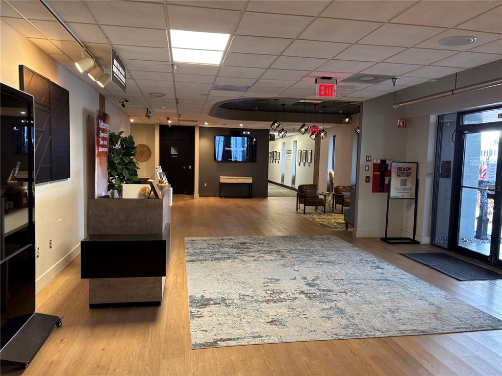 A modern lobby features light wood flooring, a large area rug, and a reception desk — 6177 LAKE ELLENOR DRIVE, ORLANDO, FL