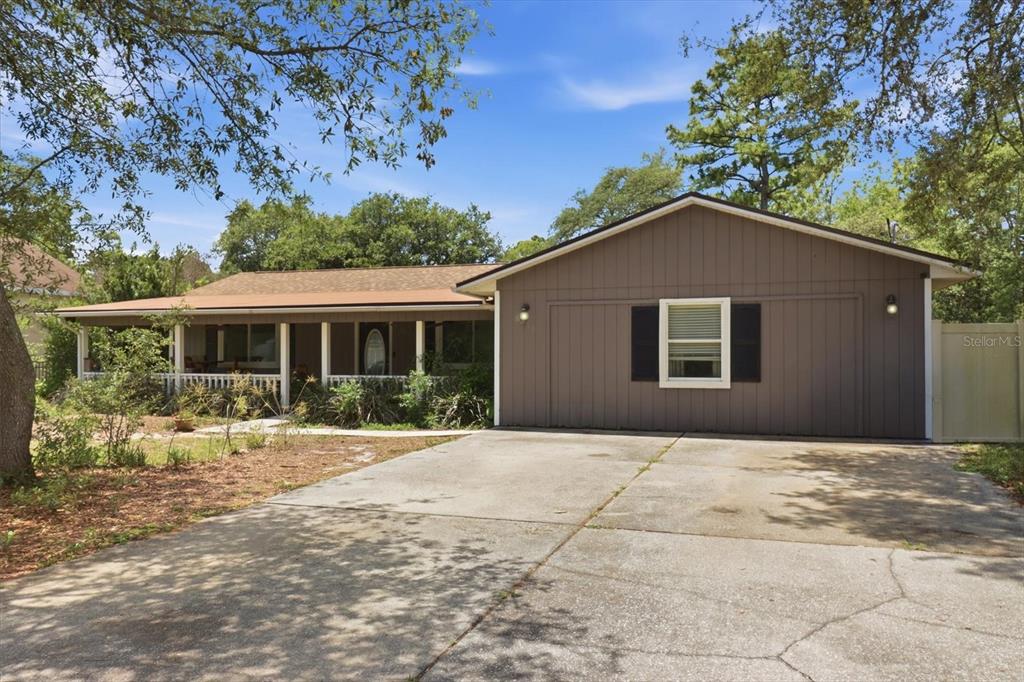 A single-story house with a brown exterior, a front porch, and a concrete driveway — 8720 N TROJAN DRIVE, CITRUS SPRINGS, FL
