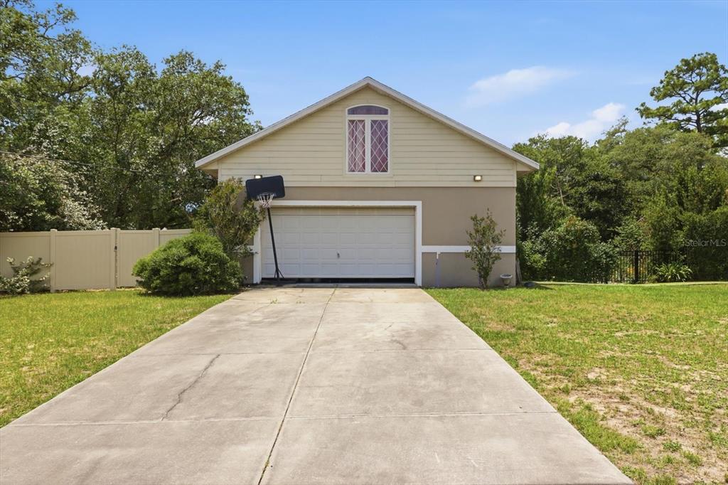 A detached garage with a concrete driveway, a basketball hoop, and an upper-level window — 8720 N TROJAN DRIVE, CITRUS SPRINGS, FL