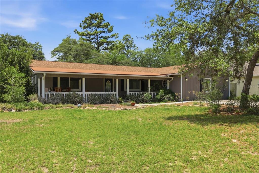 A single-story house with a covered front porch and a large grassy yard — 8720 N TROJAN DRIVE, CITRUS SPRINGS, FL