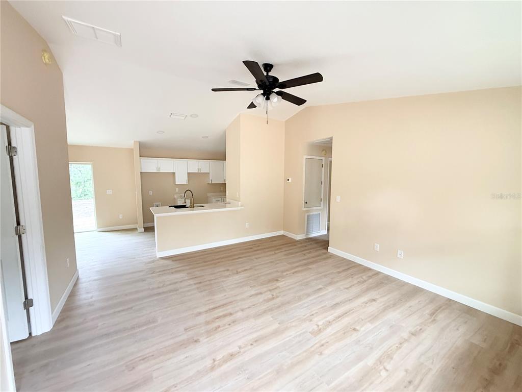 A kitchen features stainless steel appliances, white shaker cabinets, and light wood-look flooring — 9 LOCUST RUN, OCALA, FL