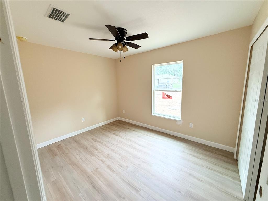 A kitchen features white cabinets, stainless steel appliances, a center island, and light wood flooring — 9 LOCUST RUN, OCALA, FL