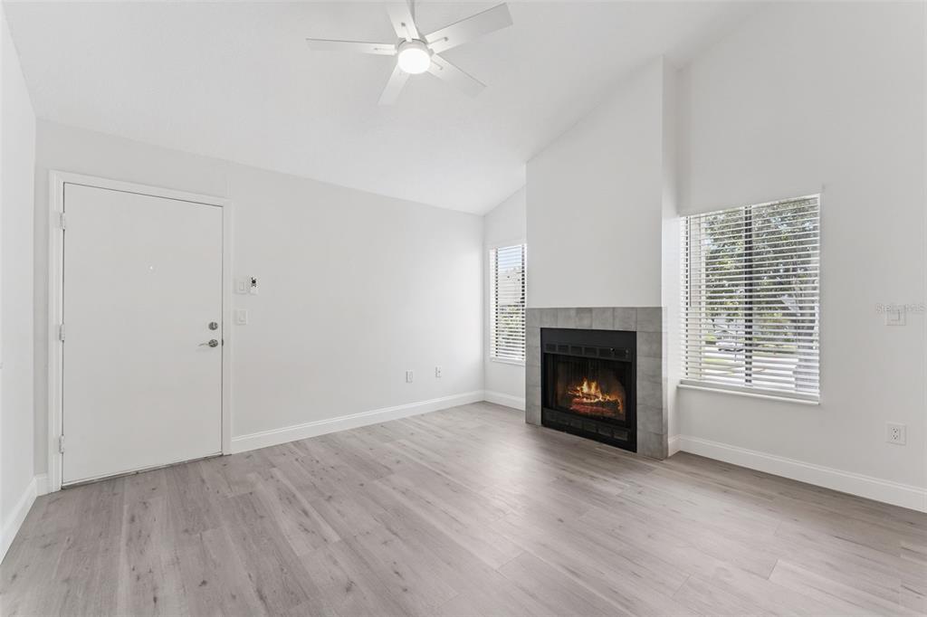 A living room features light wood-look flooring, a white ceiling fan, and a tiled fireplace — 549 SUN RIDGE PLACE UNIT 207, ALTAMONTE SPRINGS, FL