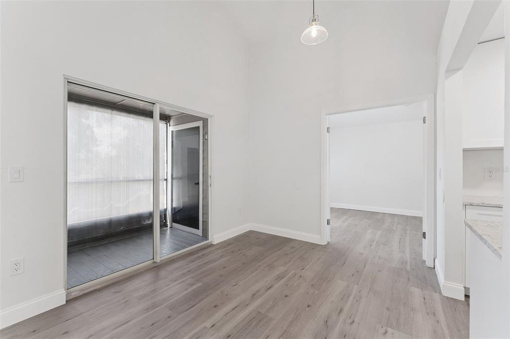 A bright room with light wood-look flooring, a sliding glass door, and a vaulted ceiling — 549 SUN RIDGE PLACE UNIT 207, ALTAMONTE SPRINGS, FL