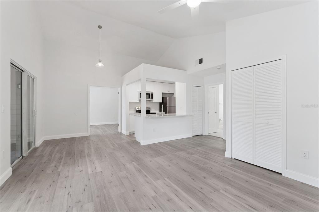 A living room with vaulted ceilings, light wood-look flooring, and an open kitchen — 549 SUN RIDGE PLACE UNIT 207, ALTAMONTE SPRINGS, FL