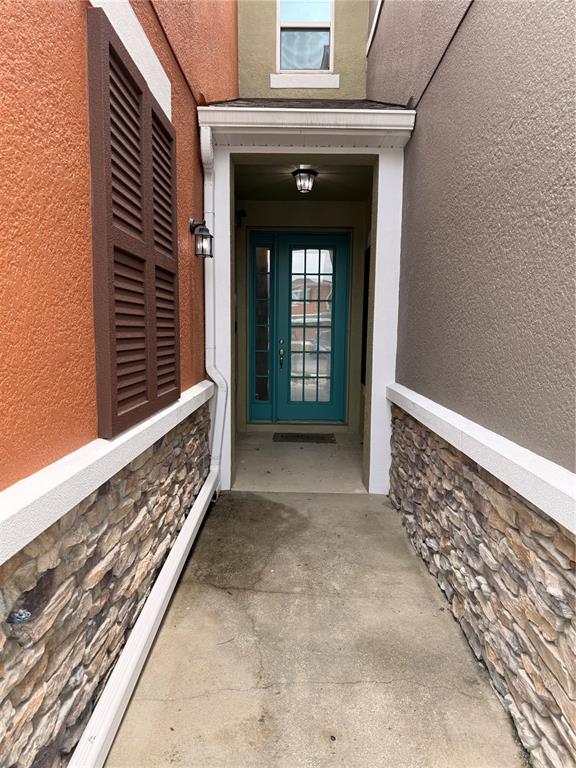 A narrow concrete walkway leads to a teal front door between two stone-accented walls — 2257 BROOKRIDGE TRAIL, SANFORD, FL