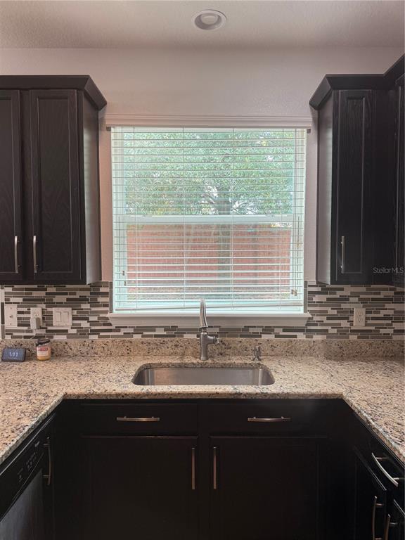 A kitchen sink area features dark wood cabinets, granite countertops, and a tiled backsplash — 2257 BROOKRIDGE TRAIL, SANFORD, FL