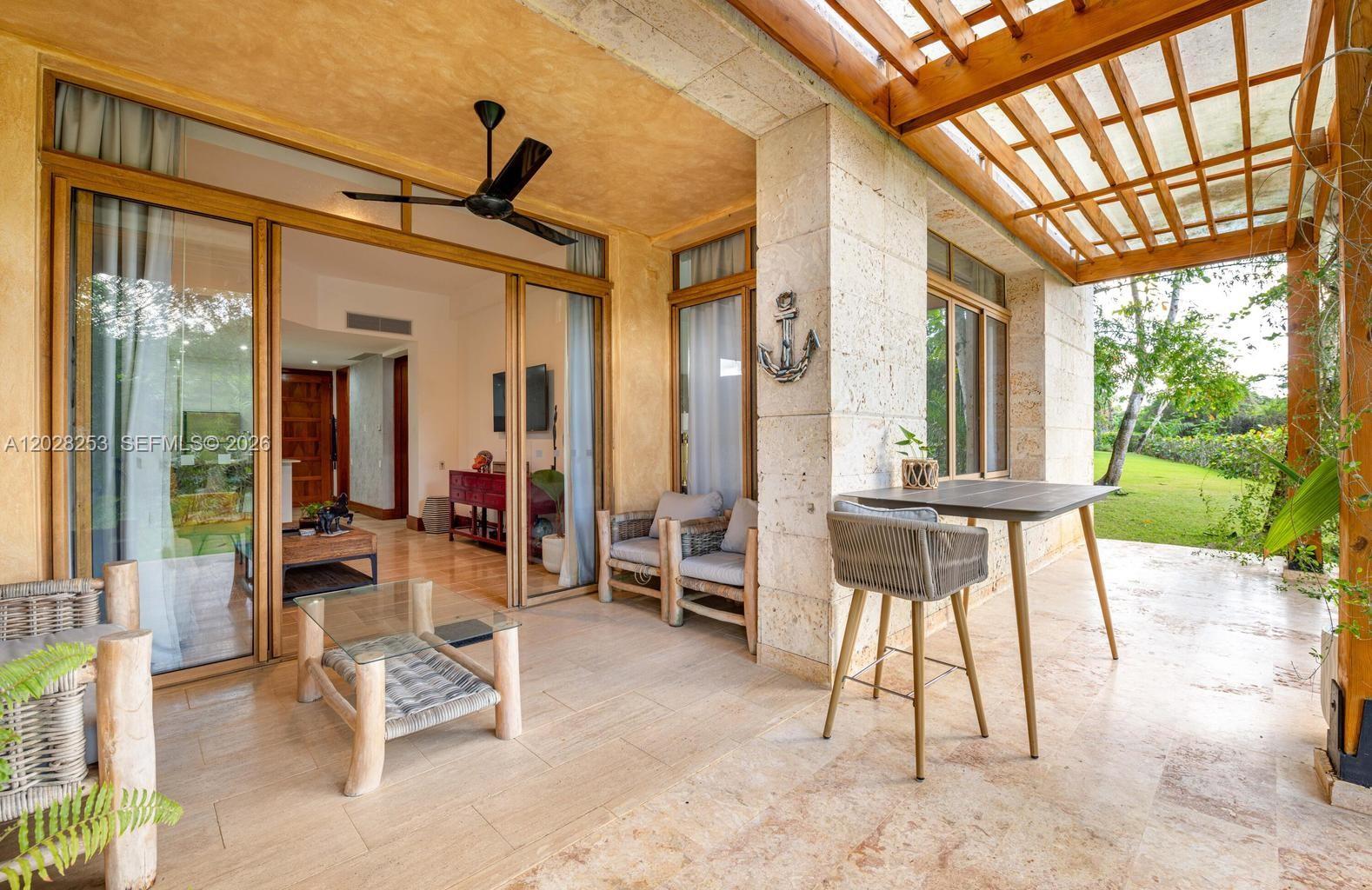 A covered patio features stone tile flooring, a wooden pergola, and glass sliding doors — FL