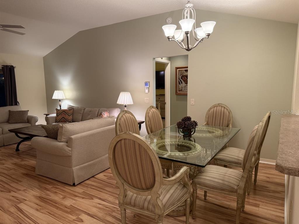 A dining area with a glass-topped table and chairs sits adjacent to a living room — 1097 HOLLYHOCK WAY, THE VILLAGES, FL