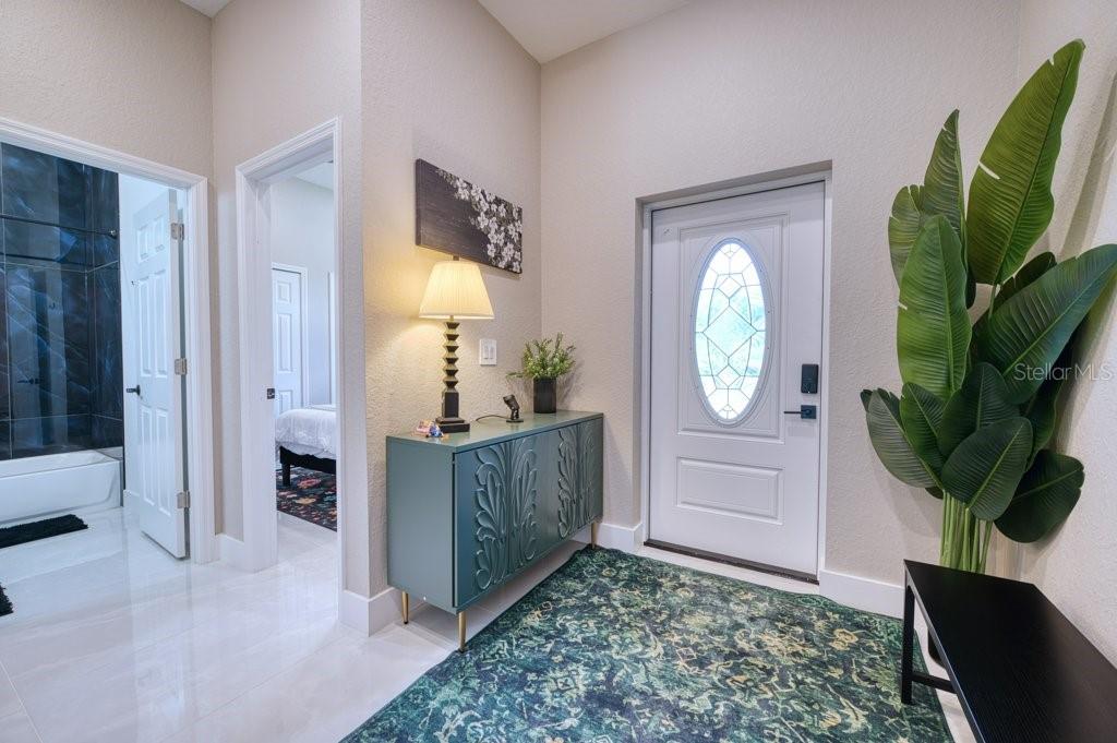 An entryway features a teal cabinet, a large potted plant, and a patterned area rug — 158 CHICKERING STREET, PORT CHARLOTTE, FL
