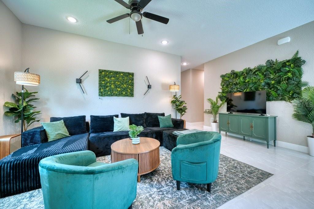 A living room features a dark sectional, two teal armchairs, and green wall decor — 158 CHICKERING STREET, PORT CHARLOTTE, FL