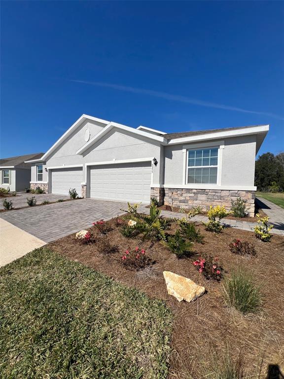 A light-colored single-story house features a two-car garage and a stone-veneer foundation — 5375 NW 48TH PLACE, OCALA, FL