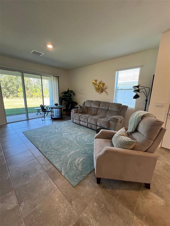 A living room features tile floors, a light-colored sofa, a recliner, and a sliding glass door — 5375 NW 48TH PLACE, OCALA, FL